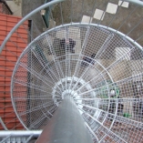 Spindeltreppe mit Gitterroststufen und Rohrrahmengeländer